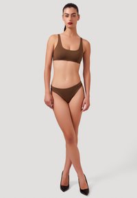 Ensemble de bikini marron avec un design simple, un tissu lisse et des coutures minimales. Assorti à des talons aiguilles noirs.