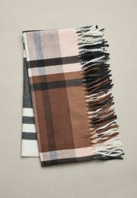 Brunternet tæppe med frynsede kanter. Har farverne beige, sort og hvid med en blød tekstur, foldet fladt på en lys baggrund.