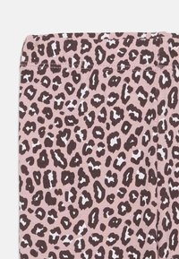 Leopardmönstrad tyg med mörkbruna fläckar på en ljusrosa bakgrund, med en slät textur och ett midjeband upptill.