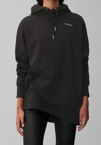 Sweatshirt noir à capuche avec une coupe décontractée, poche avant et détail de cordon. Fabriqué en tissu doux et texturé avec un accent de logo.