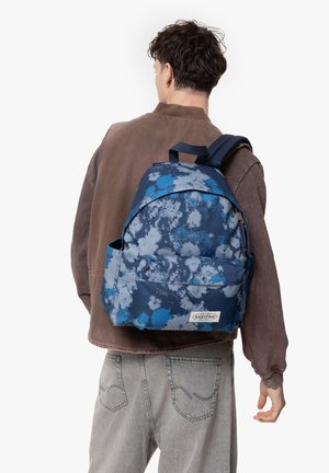 Mochila con un patrón de teñido anudado azul, hecha de una tela duradera, con un bolsillo frontal y correas ajustables.