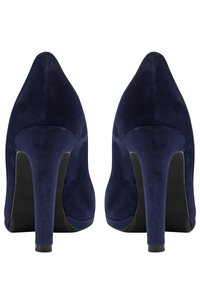 Zapatos de tacón alto azul marino, hechos de suave ante, con punta afilada y un delgado tacón de aguja. La suela es negra con una mínima marca.