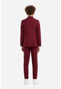 Traje burdeos para niños, que incluye un blazer estructurado y pantalones ajustados. Tejido suave, solapas estrechas y un ajuste clásico. Zapatillas blancas.