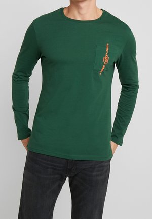 Zielona koszula z długim rękawem, wykonana z miękkiego, oddychającego materiału. Posiada kieszeń na piersi z pomarańczowym nadrukiem oraz zaokrąglony dekolt.