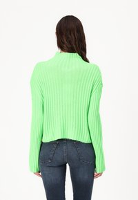 Pulover verde cu dungi, cu guler înalt, mâneci lungi și tiv scurt. Textură netedă și croială supradimensionată.