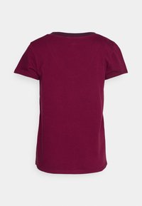 T-shirt rouge foncé à manches courtes vu de dos, avec un col rond et une texture horizontale subtile, sur un fond uni.