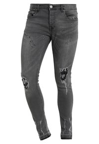 Jeans gris de corte ajustado, fabricados en denim y con detalles desgastados, incluyen dos desgastes en las rodillas y una textura ligeramente descolorida con patrones de uso sutiles.