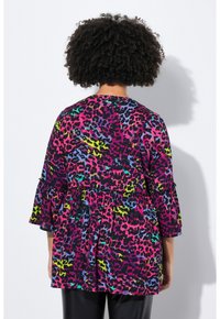 Heller, farbenfroher Oberteil mit schwarzem Grund und einem lebhaften Leopardenmuster in den Farben Pink, Grün, Blau und Lila. Volantärmel.