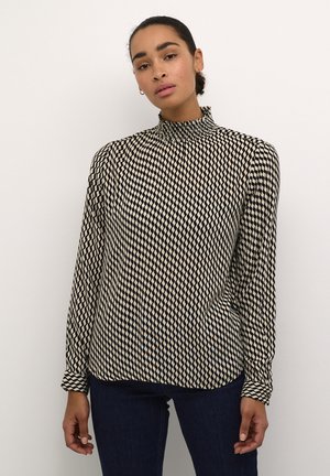 Haut à manches longues noir et crème avec un col froncé haut, présentant un motif en diamants et des poignets boutonnés. Tissu texturé avec une coupe décontractée.