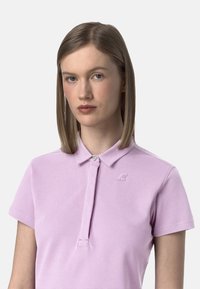 Polo shirt viola chiaro con colletto, chiusura a bottoni e logo ricamato sul petto. Realizzato in cotone, maniche corte.