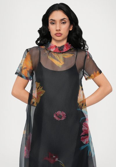 Vestido negro transparente con mangas cortas, que presenta un colorido estampado floral en rojo, amarillo y azul. Cuello redondeado y corte relajado.
