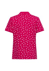 Polo à manches courtes de couleur rose vif avec un motif de cœurs blancs sur l'ensemble. Il présente un col classique et une coupe décontractée.