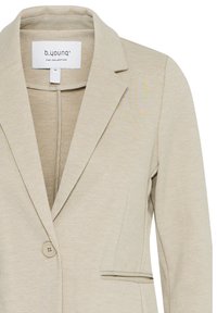 Beige enkeltknappet blazer med notched revers, to forlommer og et stofmærke inden for i kraven, der viser mærke og størrelse.