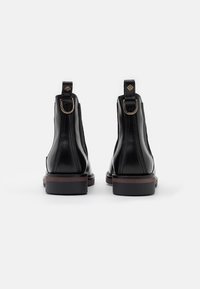 Czarne skórzane botki za kostkę o gładkiej fakturze, z elastycznymi panelami bocznymi i pętelką z tyłu. Posiadają niski, warstwowy obcas.