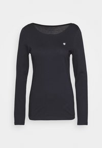Pitkähiha, pyöreäkauluksinen paita, joka on valmistettu mustasta jersey-kankaasta. Siinä on pieni valkoinen logo vasemmassa ylärinnassa ja sileä rakenne.