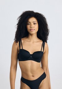 Schwarzer BH mit Spitzenverzierungen und einem Vorderverschluss. Verfügt über dünne, verstellbare Träger und eine glatte Textur, kombiniert mit passenden schwarzen Panties.
