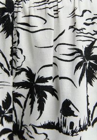 Černobílá látka s tropickými palmami a malým domem, s texturovaným pletivem a detailními liniovými vzory.