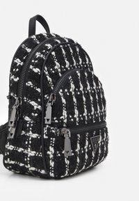 Mini plecak z czarno-białego tweedu z dwoma zapinanymi na zamek przedziałami, akcentami z ekologicznej skóry i metalowymi metkami. Kompaktowy, zaokrąglony kształt.