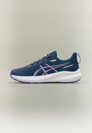 Zapatilla de correr azul marino con detalles en lila claro, suela blanca, empeine de malla transpirable y logo de la marca en un lateral sobre un fondo liso.