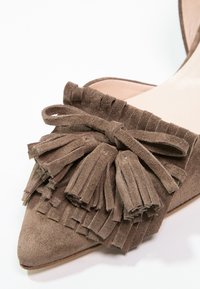 Chaussure en daim marron à bout pointu avec des franges superposées et un nœud décoratif en daim à l'avant.