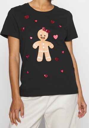 T-shirt noir avec une figure centrale de pain d'épices portant un nœud rouge, entourée de formes de cœur rouges et roses scintillantes.