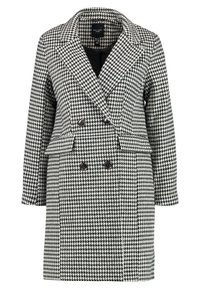 Schwarz-weißer Hahnentritt-Doppelreiher mit breiten Revers, langen Ärmeln und zwei vorderen Taschen. Mit schwarzen Knopfakzenten.