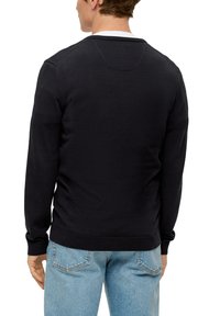 Czarny sweter z okrągłym dekoltem i prążkowanymi mankietami, noszony na jasnoniebieskich dżinsach. Prosty design, miękka tekstura i standardowy fason.