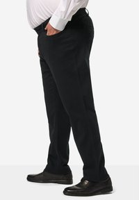 Černé bavlněné kalhoty s rovný střihem, předními kapsami a hladkým povrchem. Spárovány s černými koženými botami pro formální vzhled.