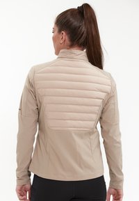 Beige jacka med en texturerad vadderad bakpanel, hög krage och släta ärmar. Har en skräddarsydd passform och subtil logotypdetalj.