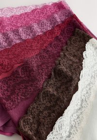 Pile de tissus bordés de dentelle dans des nuances de rose, magenta, bordeaux, marron et blanc, disposés en couches superposées sur un fond neutre.
