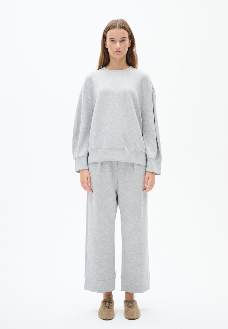 Grijze oversized sweatshirt met verlaagde schouders, gecombineerd met bijpassende brede joggingbroek, gemaakt van een zachte fleece stof.