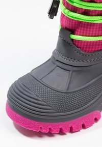 Botte d'hiver en caoutchouc noire et rose avec semelle texturée, lacets verts néon et section supérieure en tissu rose.