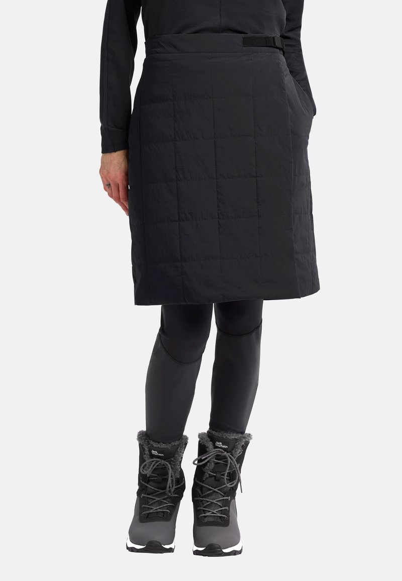Zwarte quilted rok met een rechte tailleband, zijzakken en een knielange ontwerp, gecombineerd met zwarte leggings en winterlaarzen.