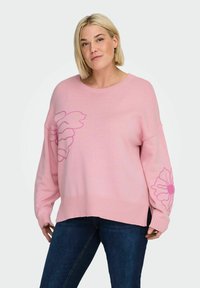 Maglione rosa lavorato a maglia con vestibilità ampia, polsini e orlo a costine, e motivi floreali in tonalità più scure sul davanti e sulla manica.