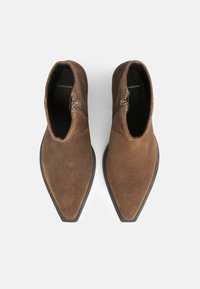 Botas de ante marrón hasta el tobillo con un diseño de punta afilada, que cuentan con una discreta cremallera lateral y un acabado de textura suave.