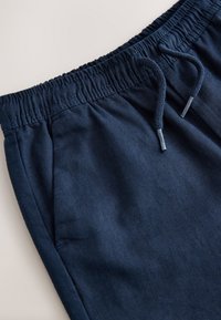 Pantalon de jogging bleu marine avec taille élastique et cordon de serrage, doté de poches latérales et d'une texture en tissu de coton doux.