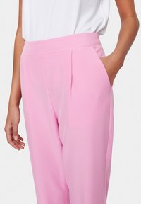 Rosa maßgeschneiderte Hose mit glatter Textur, seitlichen Taschen, flacher Vorderseite und dezenten Falten an der Taille für eine figurbetonte Passform.