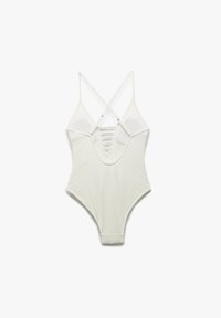 Maillot de bain une pièce blanc avec des bretelles croisées, en tissu texturé, décolleté en V profond et un dos fendu.