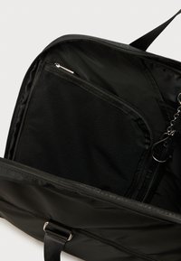 Geantă de călătorie neagră cu compartiment principal cu fermoar, buzunar interior din plasă și exterior din țesătură netedă și durabilă. Design și structură simple.