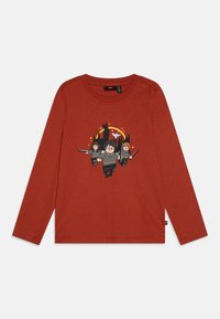 Rustfarget langermet skjorte med Lego-lignende figurer av tre trollmenn med tryllestaver, en flygende ugle og slottssilhuetter i bakgrunnen.