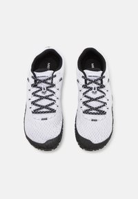 Baskets blanches de sport avec un dessus en mesh texturé, des lacets noirs et une semelle extérieure en caoutchouc noir à motifs géométriques. Nom de la marque visible.