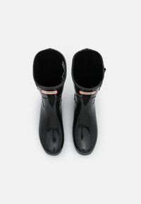 Bottes de pluie en caoutchouc noir avec une finition lisse, des bouts ronds et une hauteur de cheville courte. Présentent un logo rouge et blanc et un doublure intérieure cousue.