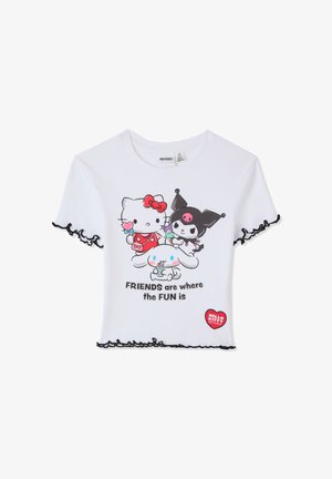 Cropped t-shirt bianca a coste con bordi neri arricciati, con grafica di quattro personaggi dei cartoni animati e la scritta "AMICI sono dove c'è il DIVERTIMENTO."