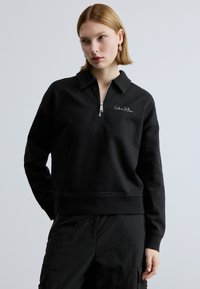 Felpa nera con zip in cotone, con colletto, orlo a coste e logo ricamato sul petto. Maniche lunghe con vestibilità comoda.