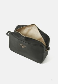 Schwarze synthetische Lederhandtasche mit einem Reißverschluss, goldener Innenauskleidung und geprägtem Logo auf der Vorderseite. Kompakte rechteckige Form.