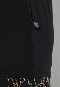 Zwart T-shirt met korte mouwen van zacht katoen, voorzien van een zijnaadlabel en een afgeronde onderzoom voor een verlengde vorm.