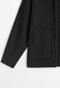 Donkergrijze cardigan met een zachte textuur, met een relaxte pasvorm, lange mouwen en twee voorzakken. Geribbelde manchetten en randdetails.
