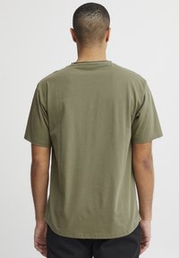 Olive green short-sleeve t-shirt made from soft fabric, featuring a round neckline and a relaxed fit, with a slightly curved hemline.