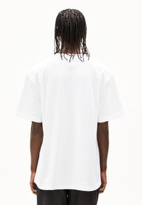 Weißes T-Shirt aus Baumwolle mit entspannter Passform, kurzen Ärmeln und Rundhalsausschnitt, das die Rückansicht mit einer glatten Textur zeigt.