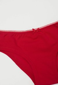 Rote Baumwollunterwäsche mit glatter Textur, ausgestattet mit einer dekorativen Schleife vorne und einer Picot-Bordüre entlang des Bunds.